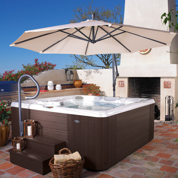 Hot Tub in backyard with accessories such as umbrella, steps, handrail and towels