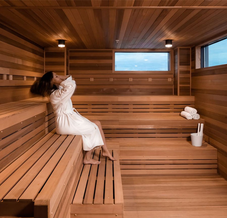 Woman in a robe sitting inside of a slatted sauna