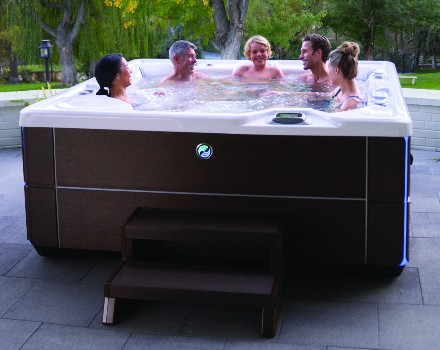 Family soaking inside of a Hot Spring Highlife Hot Tub sitting on concrete patio